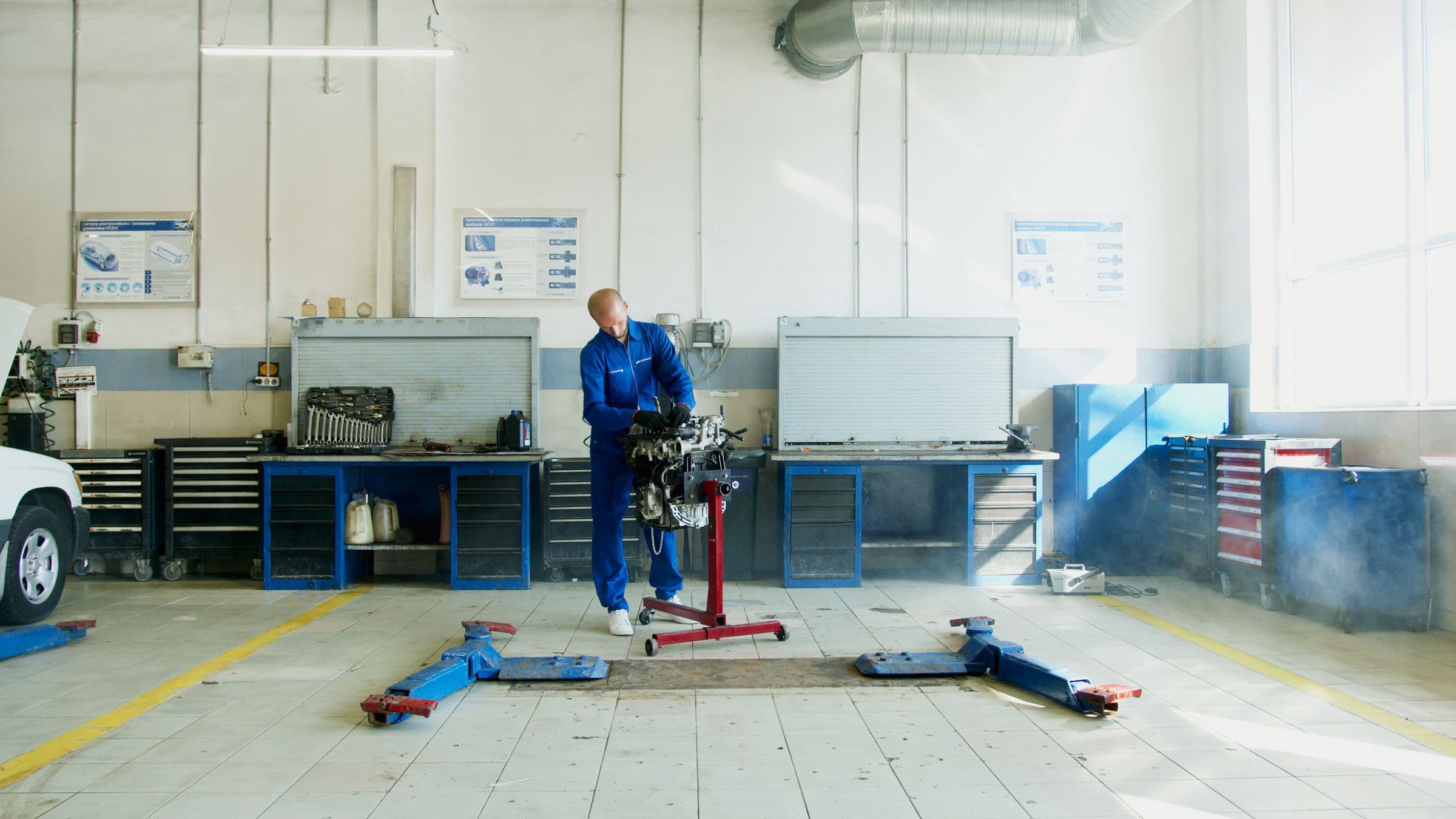 Mechanic working on an engine on a stand in a bright, clean shop