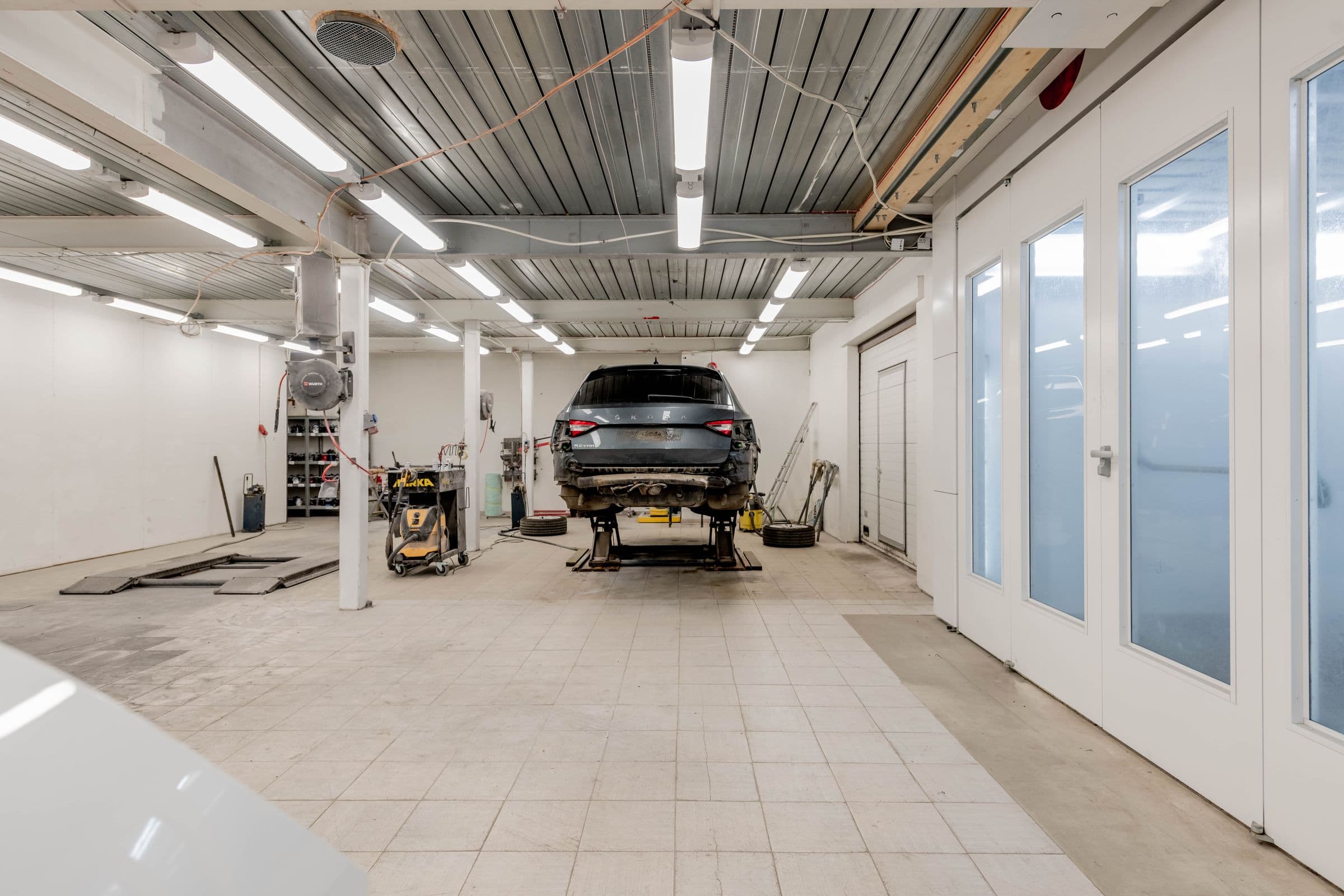 Clean, well-lit auto repair bay with a car raised on a lift