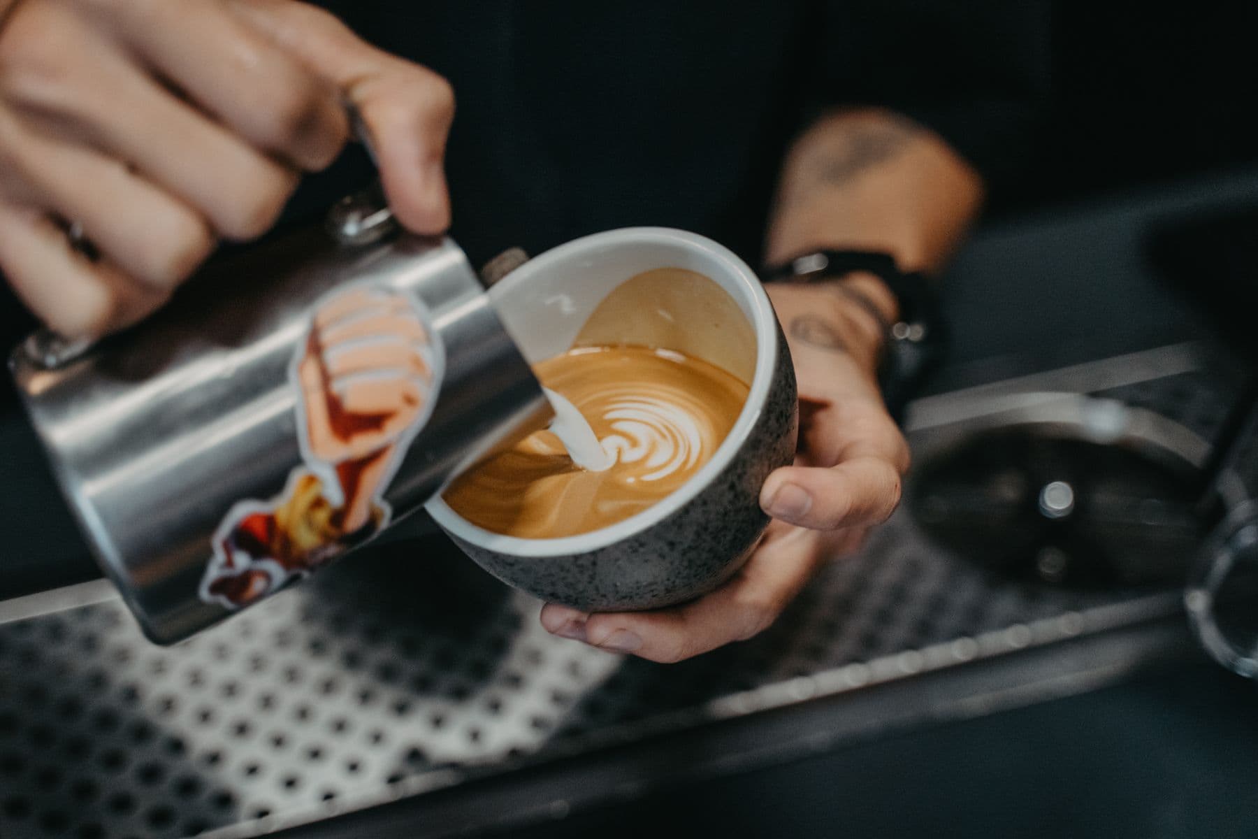 Barista pouring milk to finish a latte