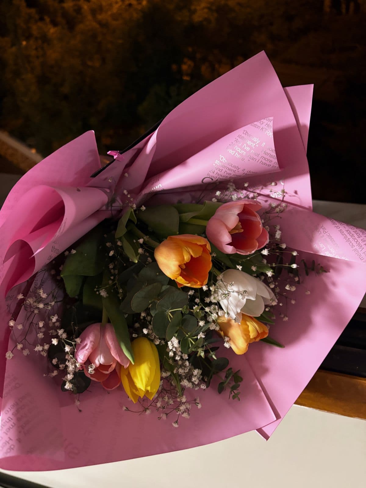 A bouquet of pink and orange tulips wrapped in pink paper