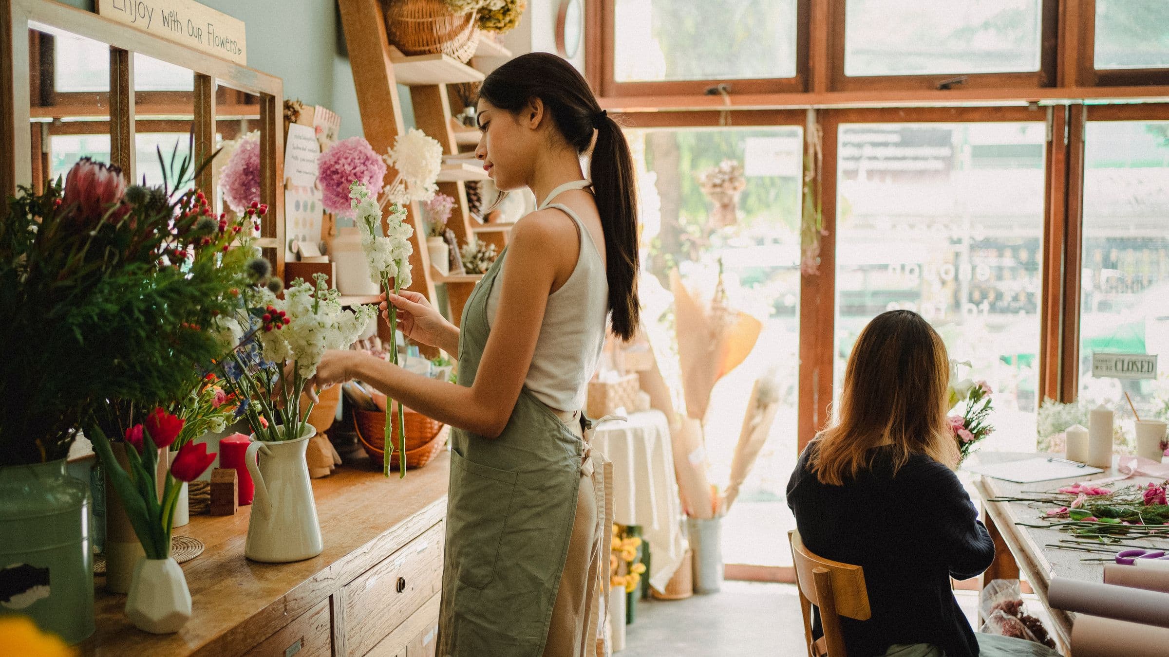 Two florists arranging bouquets in a bright flower shop