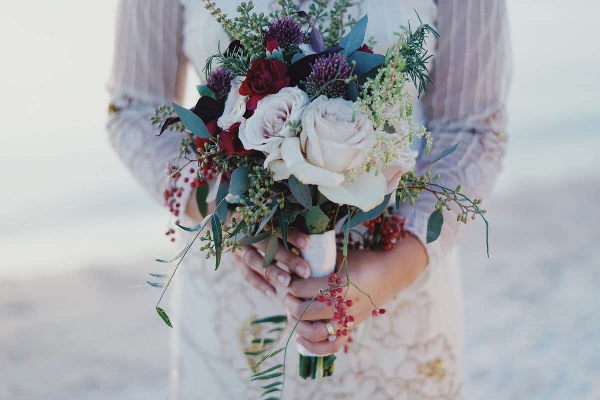 A bride holding a loose bouquet of garden roses and greenery