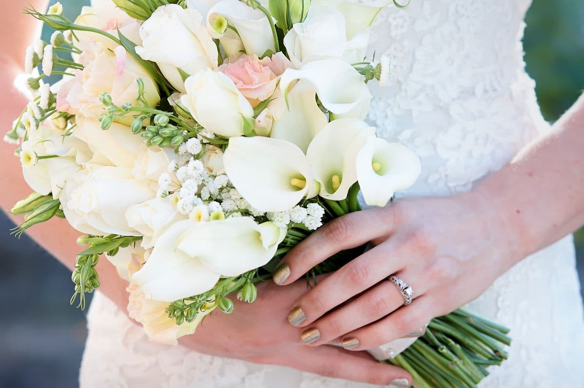A bride holding white calla lilies